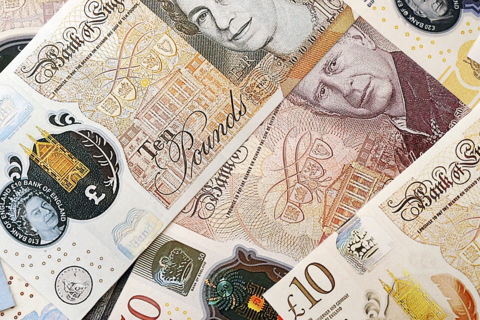 Hands counting pound notes beside a notebook